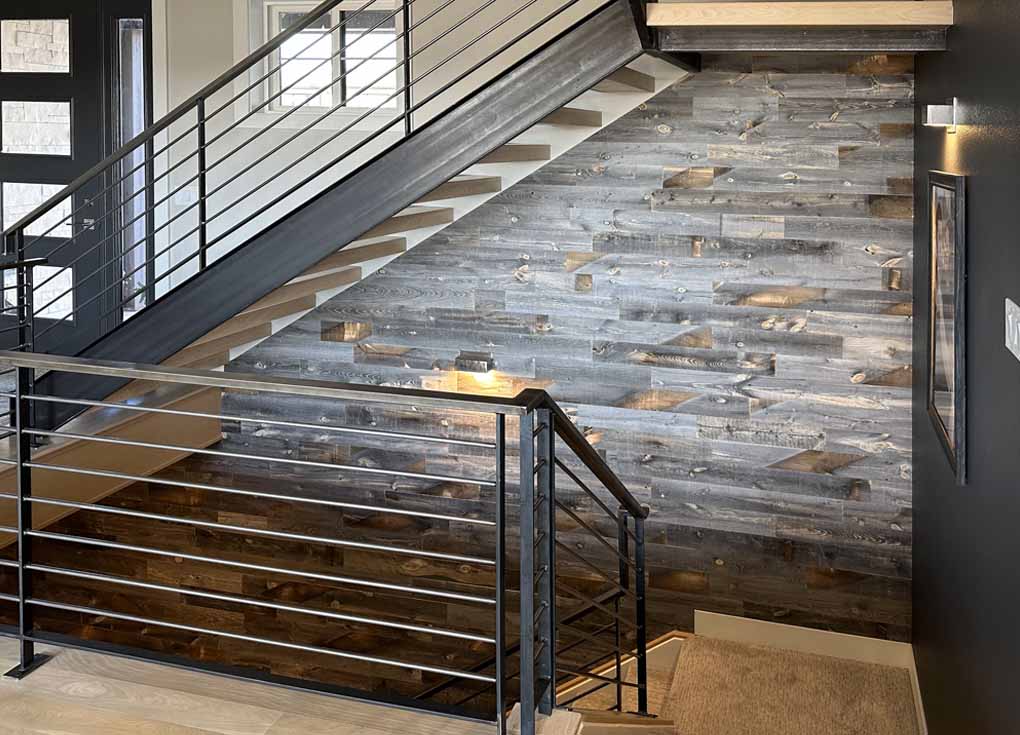 Grey reclaimed wood used on an accent wall on a staircase spanning two levels of a modern home