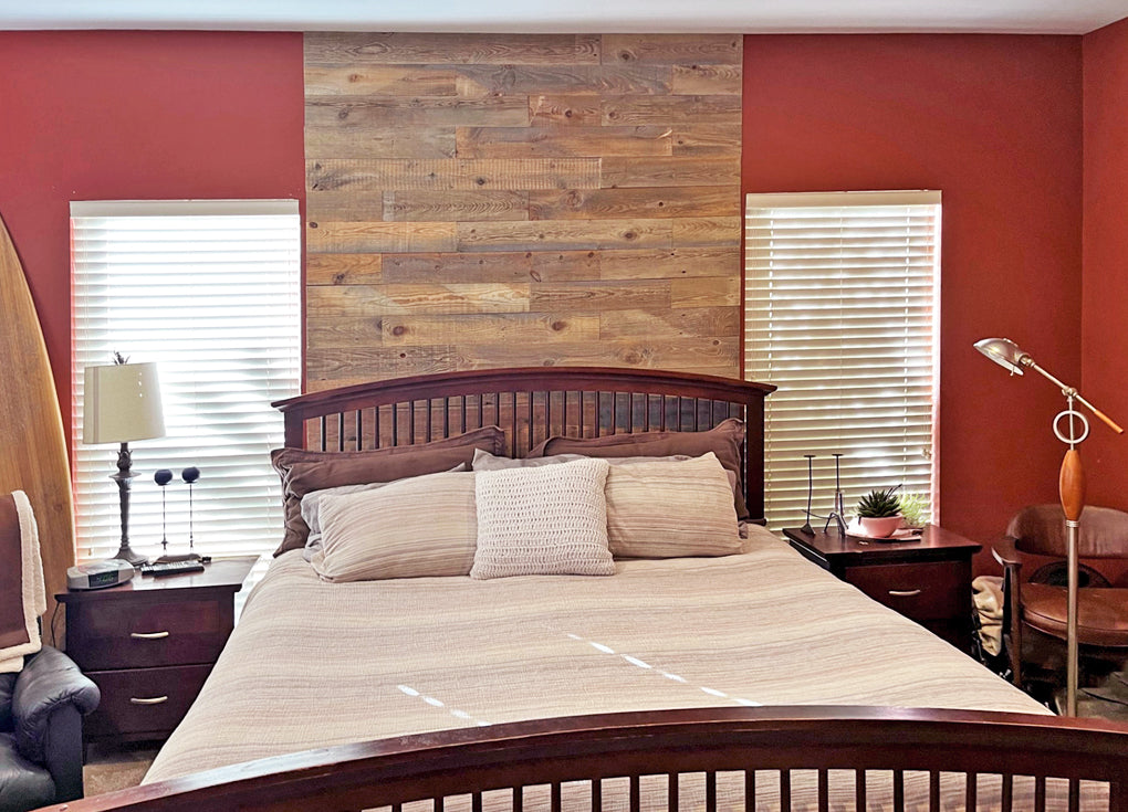 Reclaimed wood accent wall behind a traditional headboard in a bedroom with red walls 
