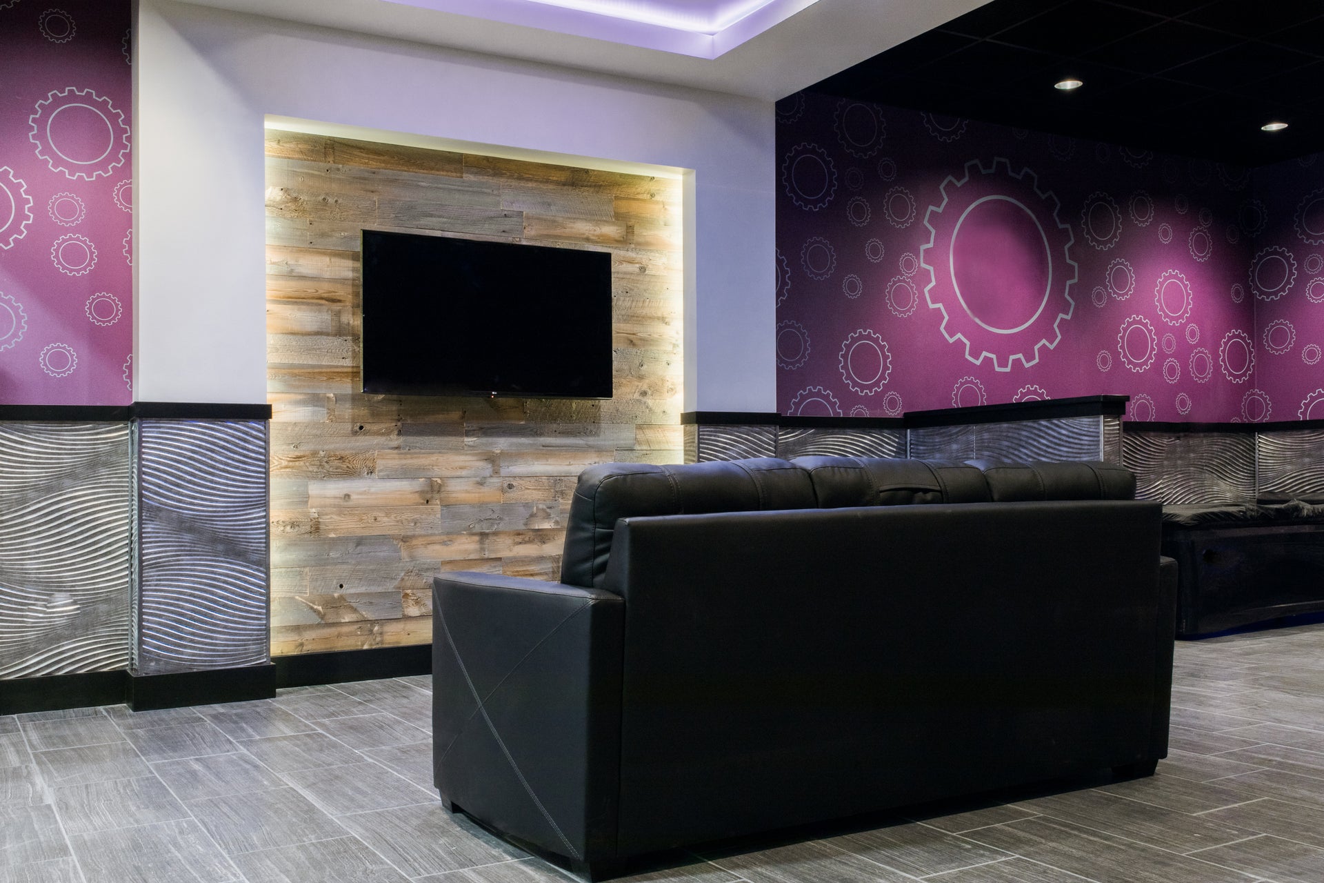 Light reclaimed wood feature wall in a Planet Fitness break area with a sofa and tv.