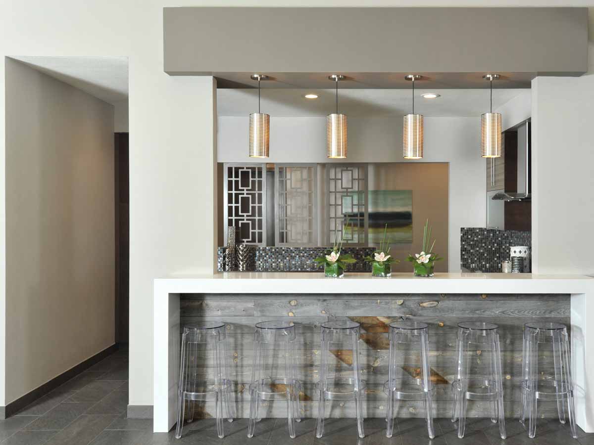 reclaimed wood cladding on a kitchen island with lucite stools in a modern home.