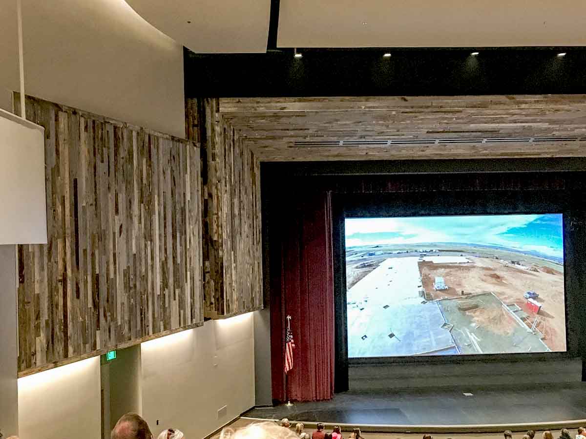 Vertical reclaimed wood wall in a high school auditorium.