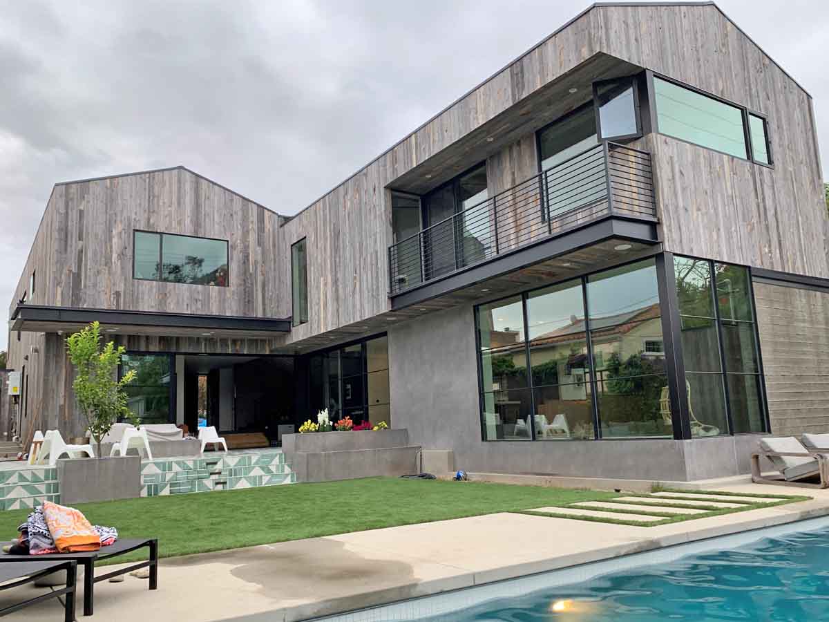 Vertical, grey reclaimed wood siding from Centennial Woods on a modern home with a swimming pool.