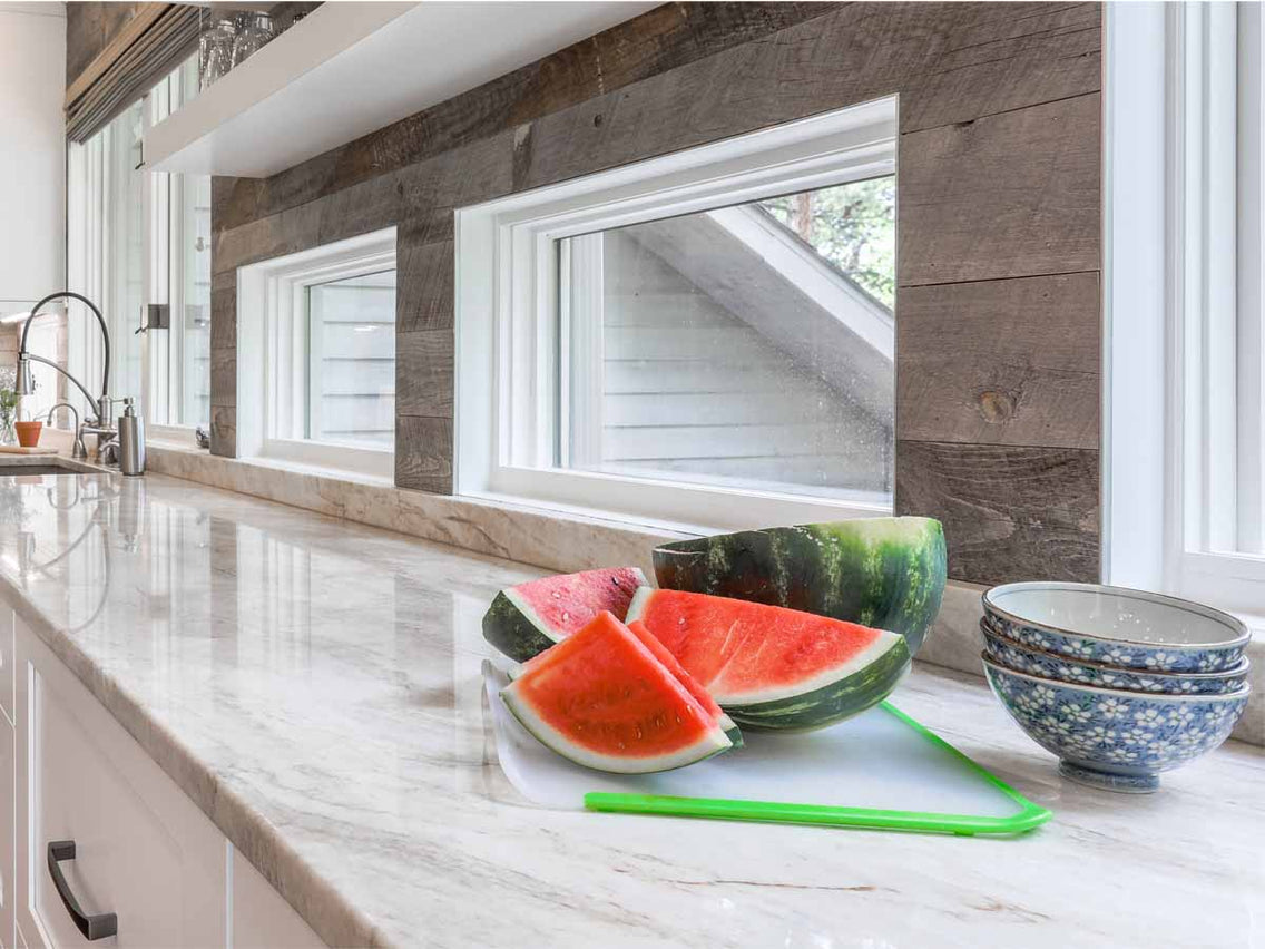 Reclaimed wood accent wall in a modern kitchen with slices of watermelon on a white marble countertop designed by Alexa Interiors out of Evergreen, CO.