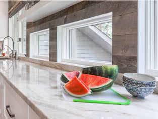 Reclaimed wood accent wall in a modern kitchen with slices of watermelon on a white marble countertop designed by Alexa Interiors out of Evergreen, CO.