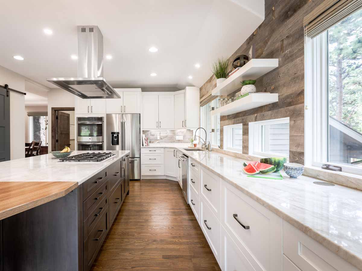 reclaimed wood accent wall in a modern white kitchen with black accents.