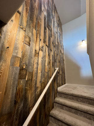 Accent wall next to a staircase made with Salvaged Wood Planks from Centennial Woods.