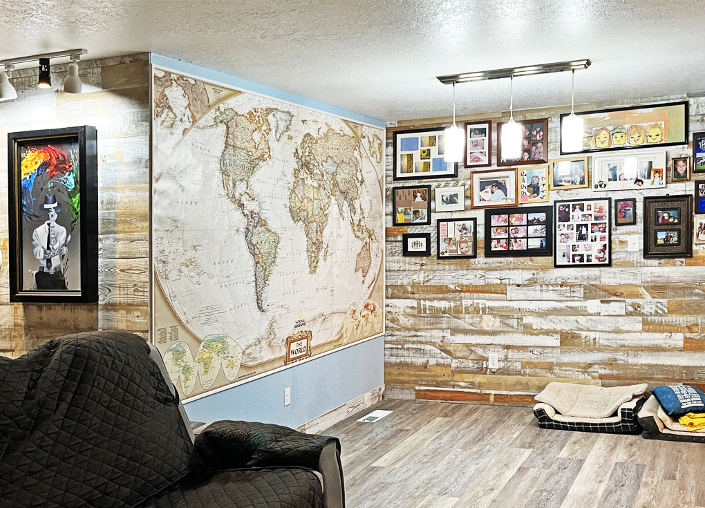 White reclaimed wood in the Casper finish from Centennial Woods on 2 walls in a living room with a large map on a wall and a photo collage on another wall