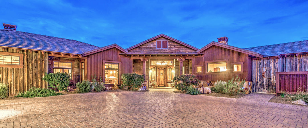 Modern rustic home at dusk clad in muli-colored reclaimed wood boards and corrugated metal siding.