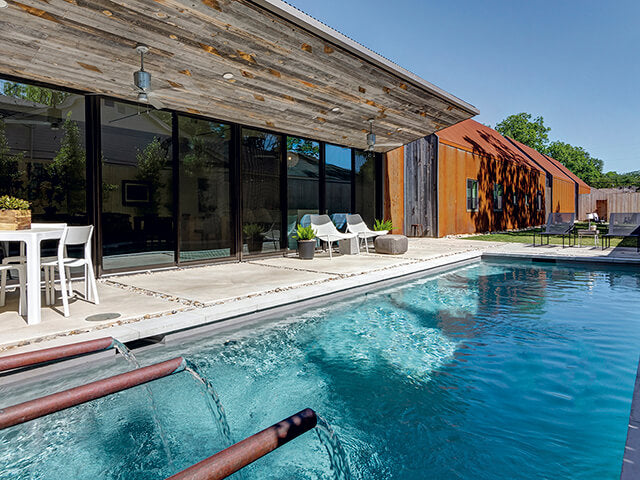 Modern home with a swimming pool featuring grey reclaimed wood soffits and walls.