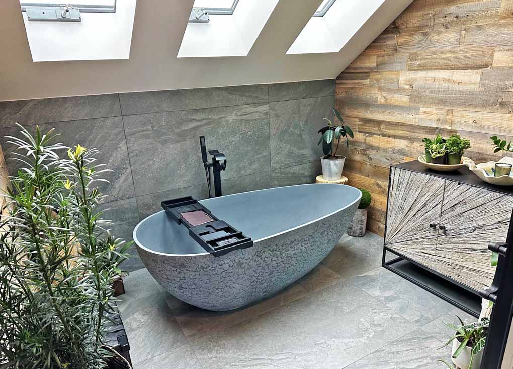 Modern zen bathroom with a tub slate wall, and brown reclaimed wood wall with many plants.