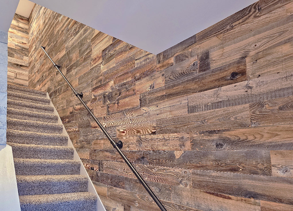 Reclaimed wood walls on a staircase with an industrial hand rail