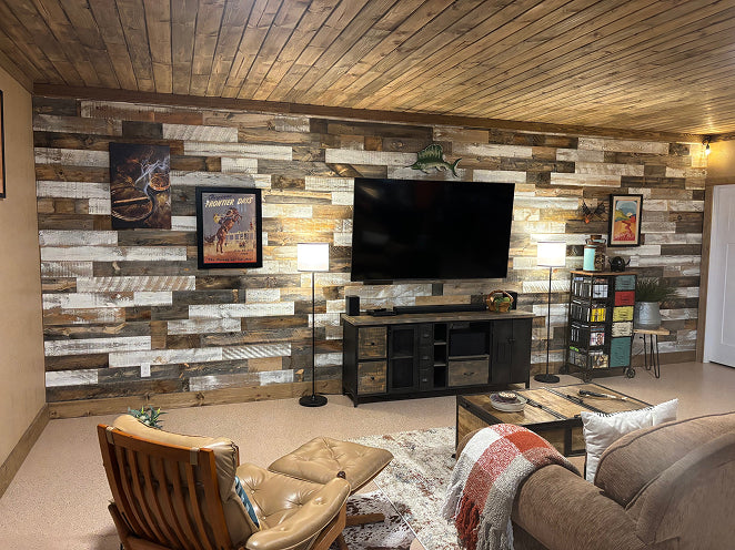 Living room with mixed-tone reclaimed wood wall paneling, a wood ceiling, and a wall-mounted television.