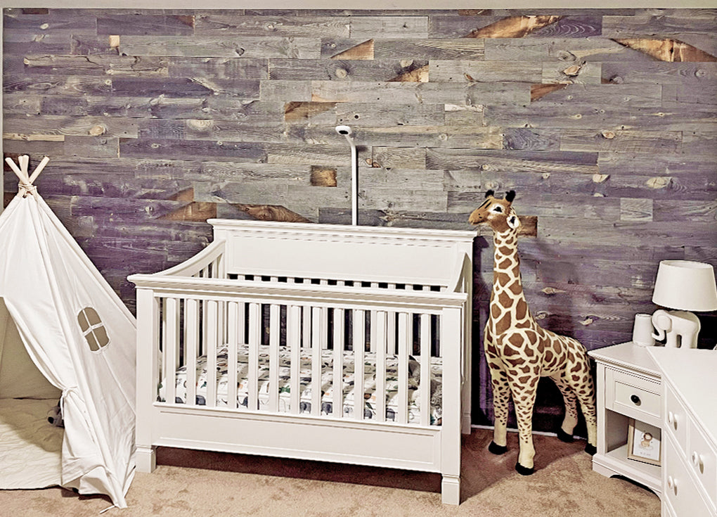 Baby nursery with white furniture, a toy giraffe, and a gray reclaimed wood wall in the Laramie finish