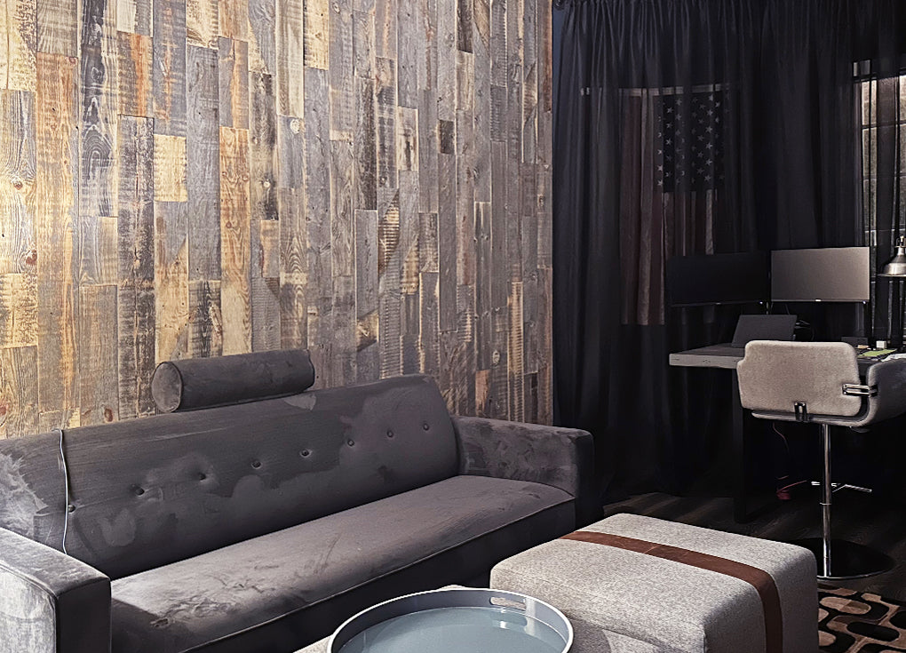 Reclaimed wood plank wall installed vertically in a darkened room with a gray sofa
