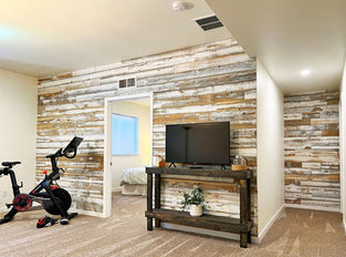 Distressed whitewash wood paneling on a wall in a tv room with an exercise bike.