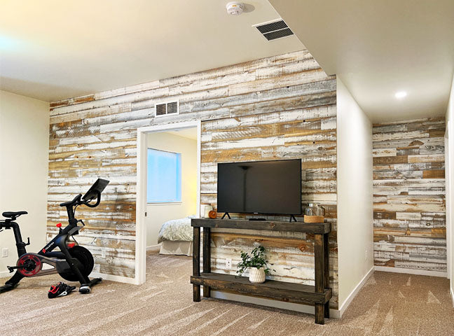 Distressed whitewash wood paneling on a wall in a tv room with an exercise bike