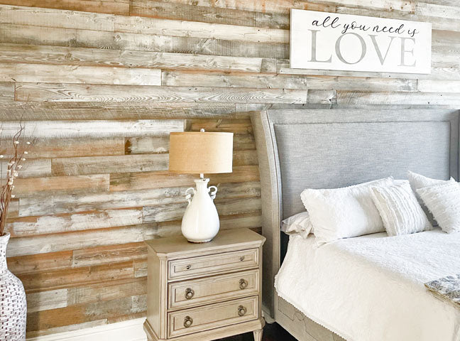 Distressed whitewash wood paneling on a wall in a bedroom with word art decor.