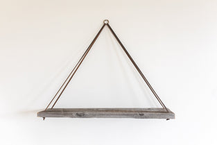 grey reclaimed wood wall shelf with ringed thin leather straps
